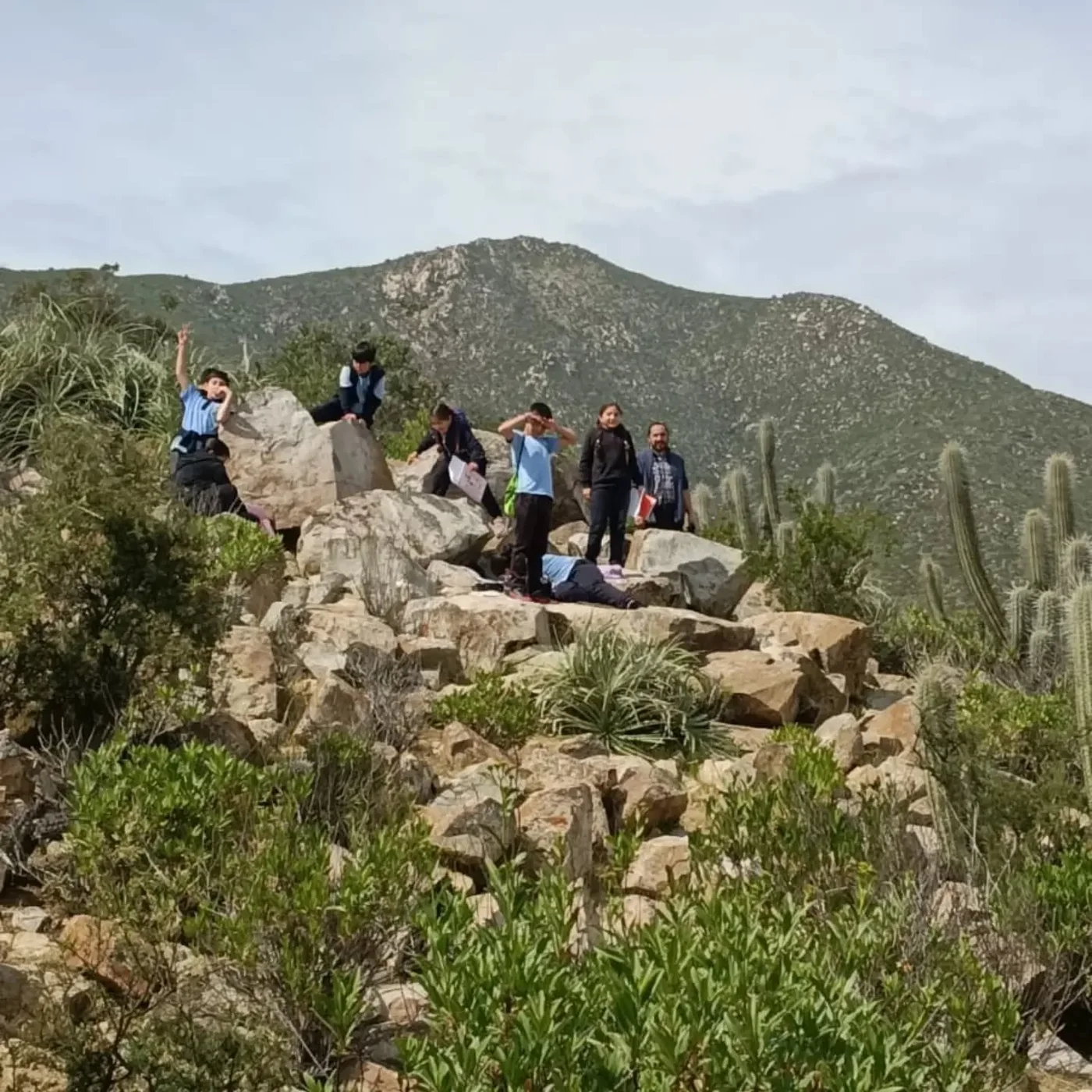 Grupo de estudiantes y un adulto en un entorno de rocas y vegetación