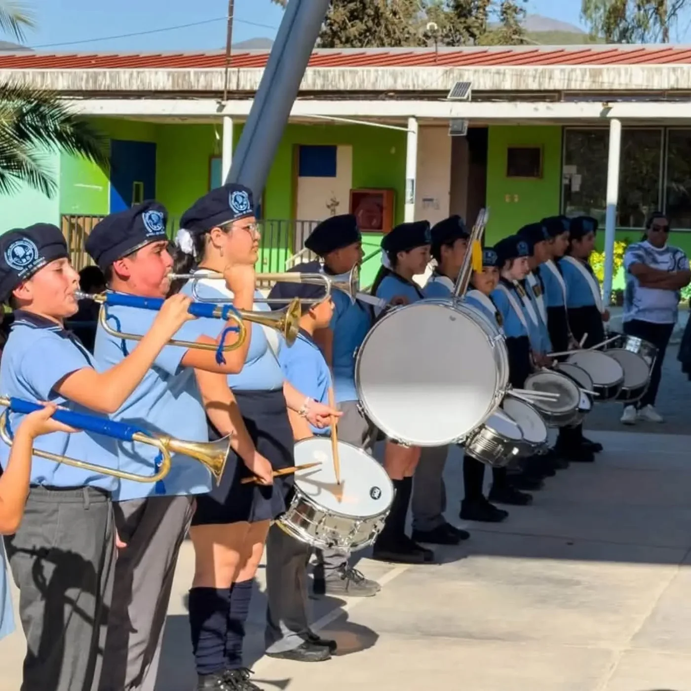 Integrantes de la banda escolar con instrumentos de viento y percusión en el patio