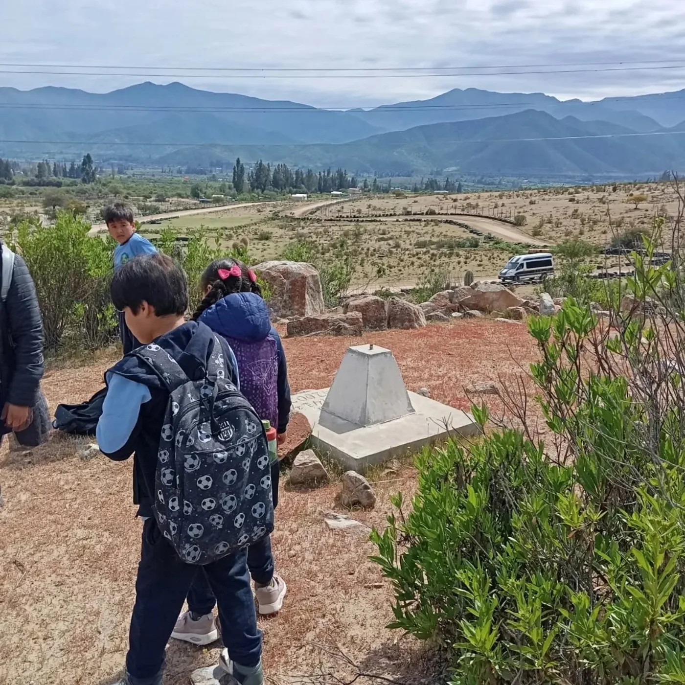 Estudiantes recorriendo un sendero al aire libre con el valle y los cerros al fondo